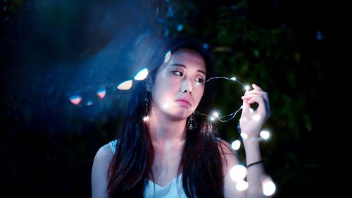 Woman holding illuminated string light at night