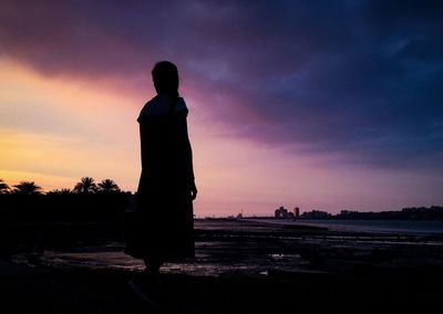 Silhouette man standing on beach against sky during sunset