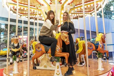 Couple of multiethnic young women having fun after shopping on carousel