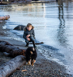 Portrait of boy with dog at lakeshore during sunset