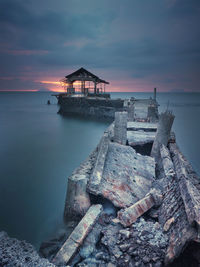 Pier over sea against sky at sunset