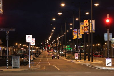 Illuminated street against sky at night