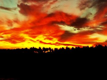 Silhouette landscape against dramatic sky during sunset