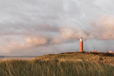 Lighthouse on field against sky
