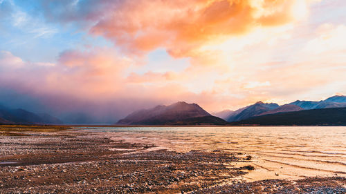 Scenic view of lake and mountains against sky during sunset