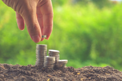 Close-up of person stacking coins on field