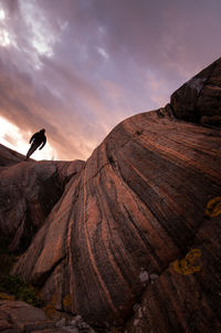 Man standing on rock against sky