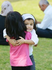 Cute sibling hugging on field