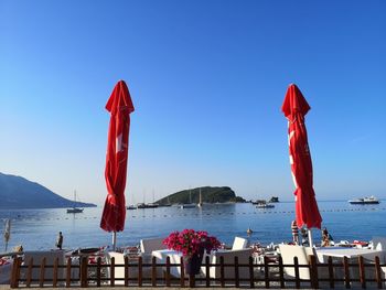 Red flag on sea against clear blue sky