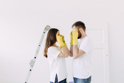 Happy smiling married couple engaged in renovation repair in the room of the house preparing to move