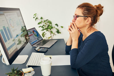 Young woman using mobile phone while sitting on table