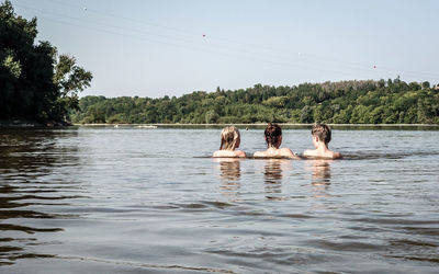 Rear view of woman and kids swimming in lake