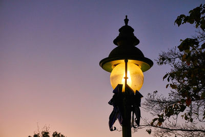 Low angle view of illuminated street light against sky at sunset