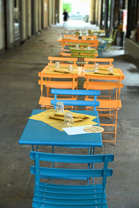 Empty chairs and table on footpath by building