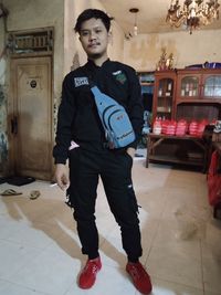 Portrait of young man looking down while standing on tiled floor