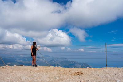 Full length of boy standing on sea shore against sky