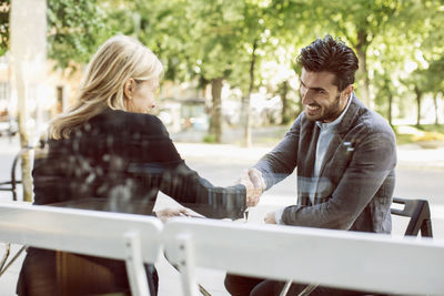 Business partners shaking hands at sidewalk cafe