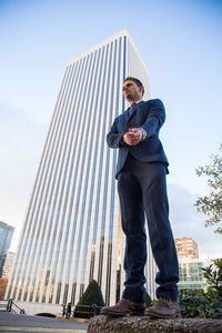 Low angle view of businessman standing against building in city