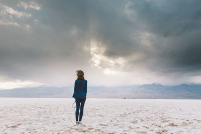 Rear view of woman standing on sand against sky