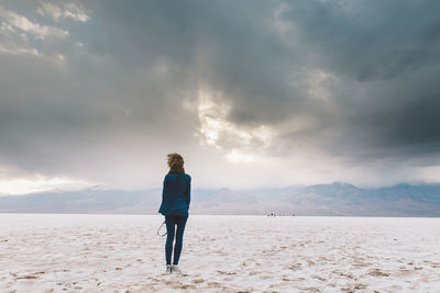 Rear view of man standing on sand against sky