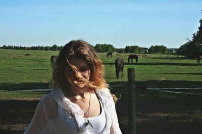Portrait of beautiful woman on field against sky