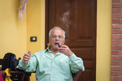 Portrait of senior man smoking pipe at home