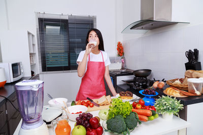 Woman looking away while standing at kitchen
