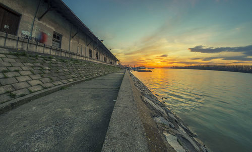 Scenic view of sea by buildings against sky during sunset