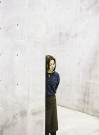 Thoughtful woman leaning on old wall