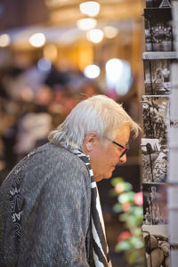 Side view of man looking at illuminated store