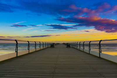 Pier over sea against sky during sunset