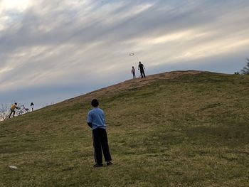 Rear view of people on field against sky