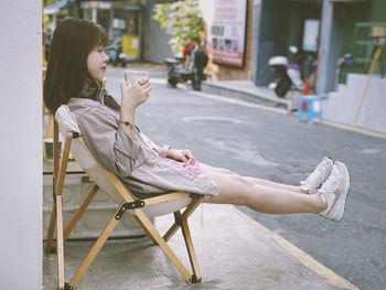 Side view of woman sitting on chair