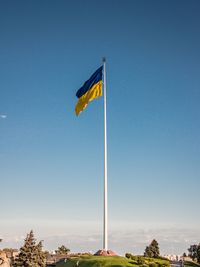 Low angle view of flag against clear blue sky