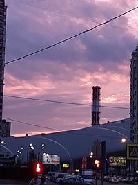 Cars on illuminated street against sky at sunset