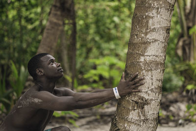 Side view of young man standing in forest