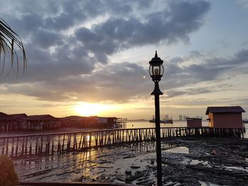Street light by building against sky during sunset