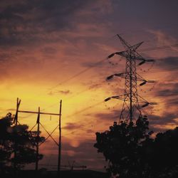 Low angle view of electricity pylon at sunset