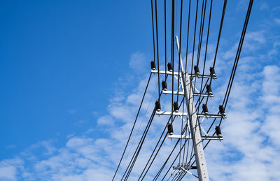 Low angle view of electricity pylon against blue sky