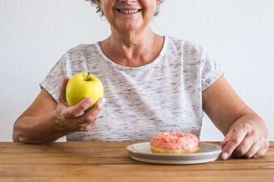 Midsection of woman eating fruits on table