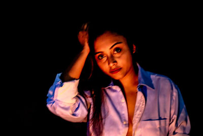 Portrait of young woman against black background