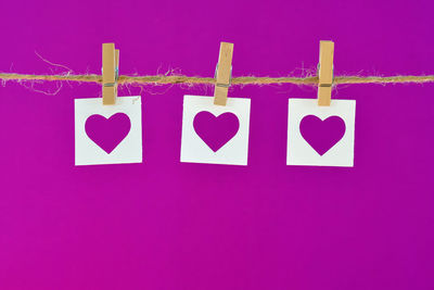 Close-up of heart shape hanging on pink background