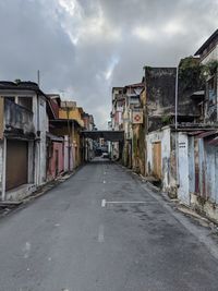 Empty road amidst buildings against sky in city