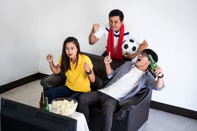 Friends cheering while watching soccer on tv
