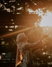 Woman in hijab standing against trees