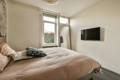 Low section of woman sitting on bed at home