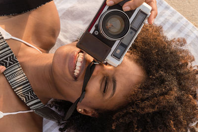 Portrait of a woman with afro hair at the beach shooting on film camera