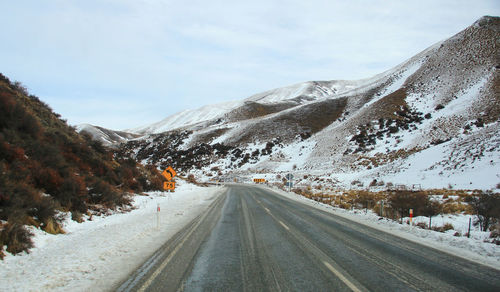Road amidst snow covered mountains against sky