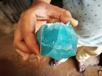 Low section of man holding blue mineral