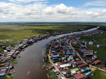 Aerial view of townscape by river against sky